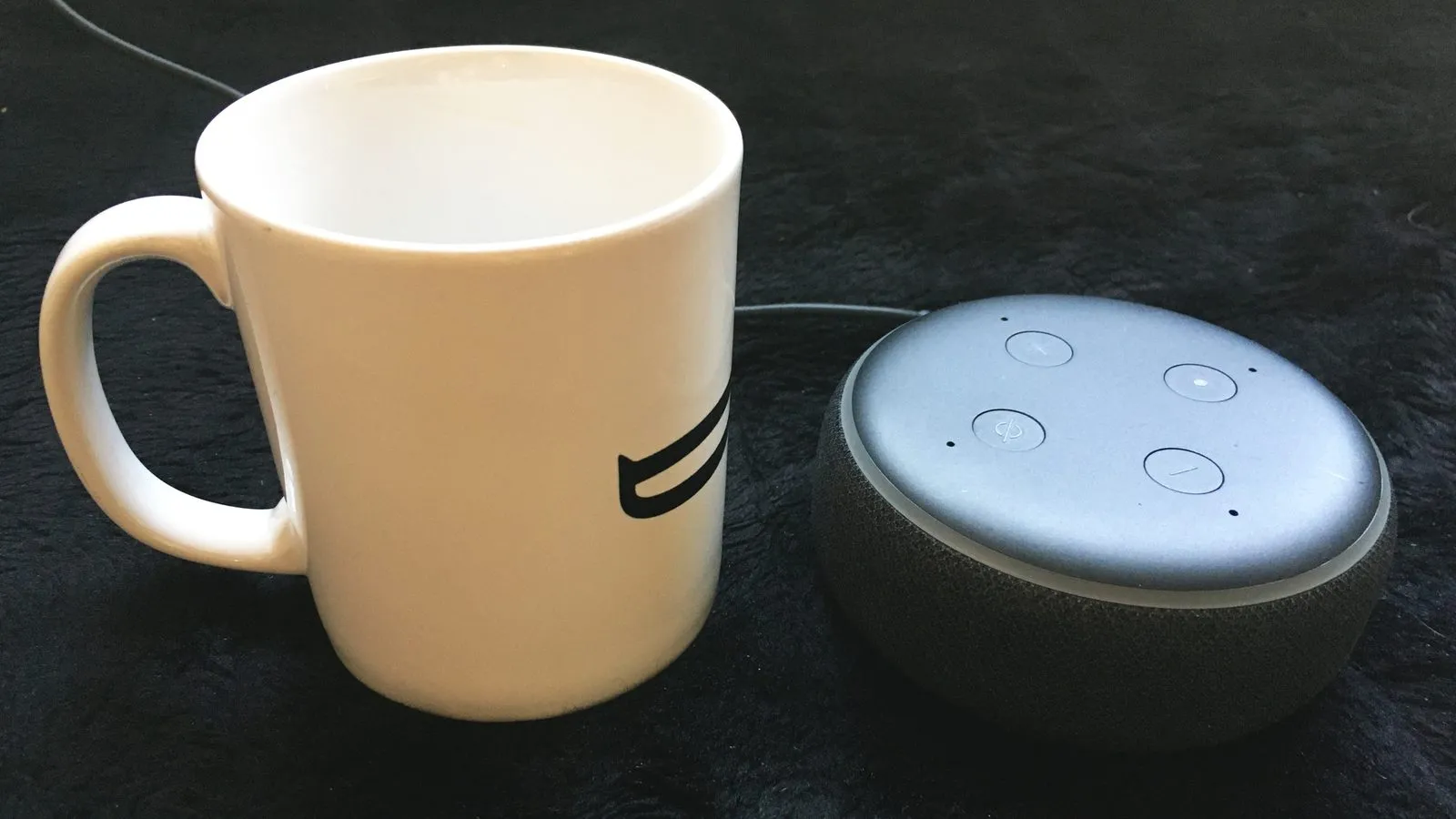 Smart speaker Echo Dot ao lado de uma caneca de café, mostrando o tamanho real do aparelho.