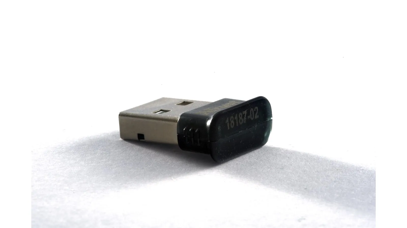 Adaptador Bluetooth USB nano, do tamanho de uma unha, sobre fundo branco de estúdio.