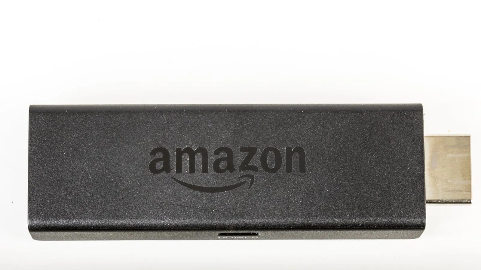 Fire TV Stick preto com o logotipo da Amazon e o conector HDMI à mostra, sobre fundo branco.
