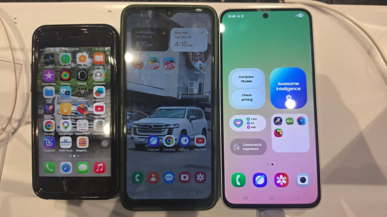Three phones side by side on a store counter, with a Galaxy A-series phone powered on at the right.