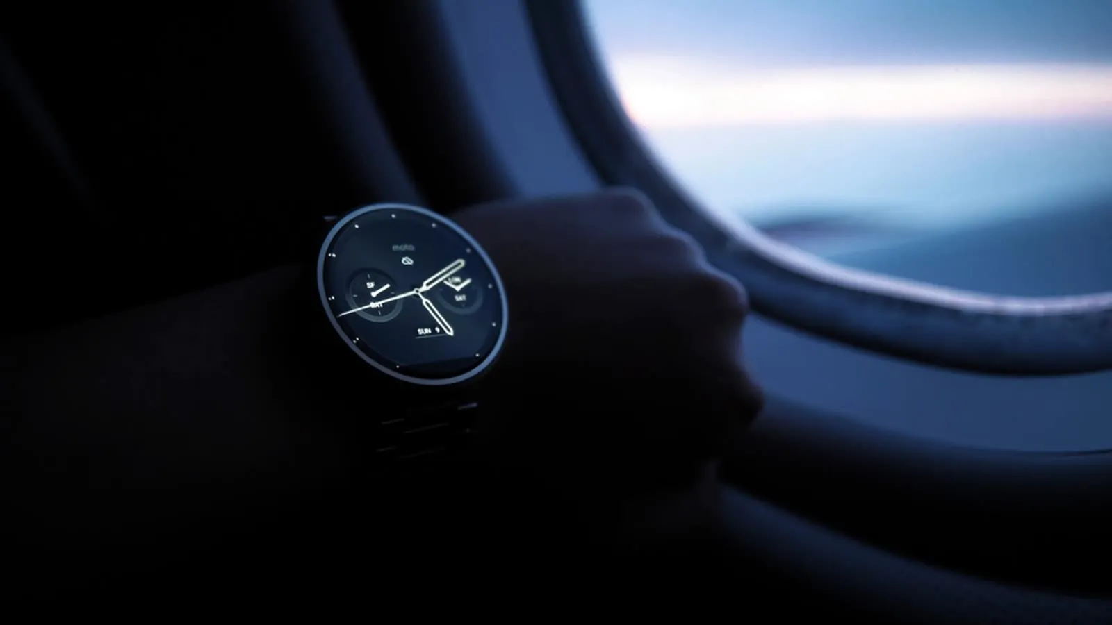 Smartwatch de mostrador redondo no pulso de uma pessoa perto da janela de um avião.